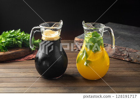 Kvass and lemonade in glass jugs on wooden table 128191717