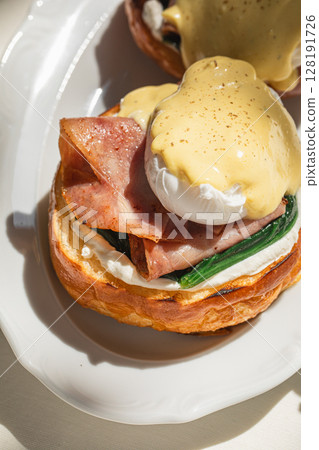 Portion of benedict eggs with sauce and brioche 128191726