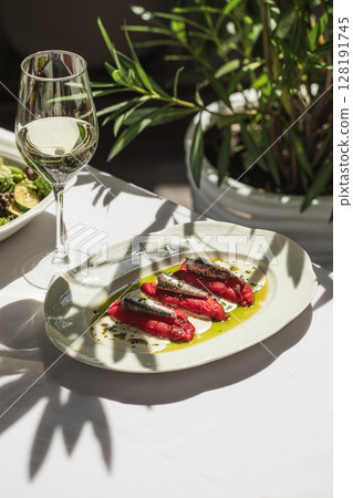 Portion of baked pepper appetizer with small fish 128191745