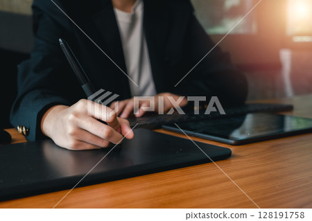 A person in a suit using a digital tablet and stylus at a wooden desk, highlighting modern technology in a professional environment. 128191758