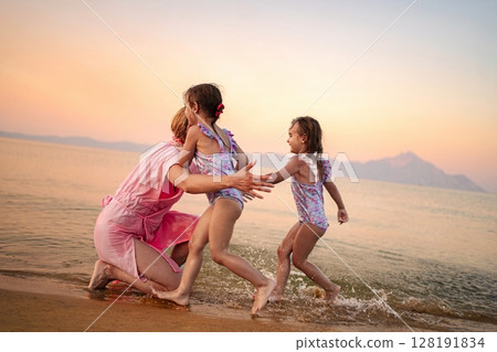 Joyful family moments as children play by the tranquil ocean waves Joyful family moments as children play by the tranquil ocean waves 128191834