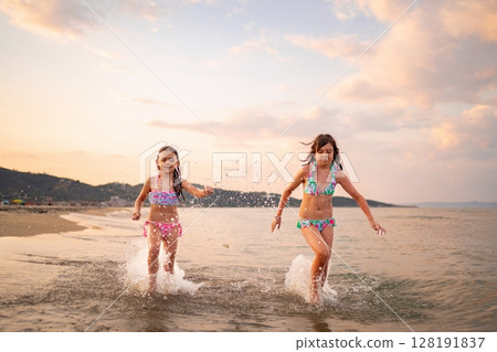 Family enjoys sunset beach play with joyful laughter and splashes Family enjoys sunset beach play with joyful laughter and splashes 128191837