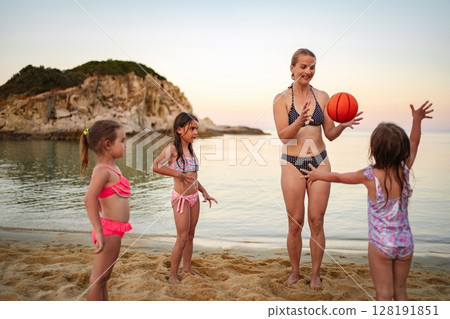 Family enjoying a playful sunset moment with a basketball at the beach Family enjoying a playful sunset moment with a basketball at the beach 128191851