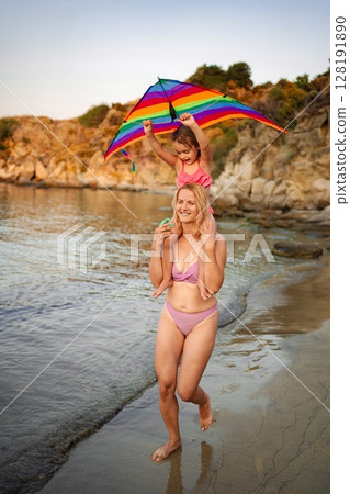Family has fun on a sunny beach with laughter and an umbrella 128191890