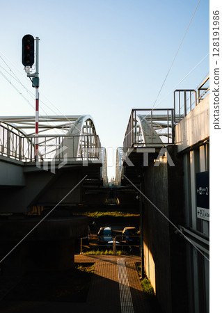 Low angle view capturing railway bridge adorned with red traffic light, while cars sit parked underneath, set against sunny day in Krakow, Poland, showcasing urban architecture. Railway bridge view 128191986