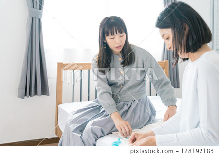 母親和女兒在臥室準備嬰兒的衣服 128192183