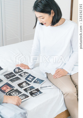 母親和女兒正在查看超音波影像,熱切地等待寶寶的出生 母親和女兒正在查看超音波影像,熱切地等待寶寶的出生 128192191