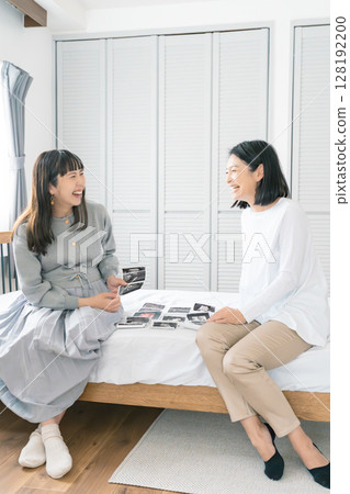 Mother and daughter looking at ultrasound images, eagerly awaiting the birth of their baby 128192200