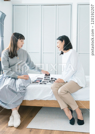 Mother and daughter looking at ultrasound images, eagerly awaiting the birth of their baby 128192207