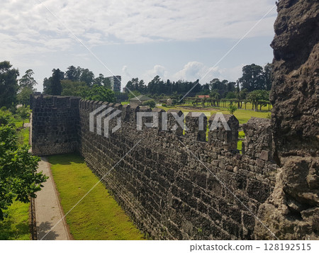 Stone wall of an ancient roman fortress on a sunny day with clouds in the sky 128192515