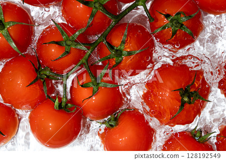 Fresh Tomatoes Splashing in Water Overhead View Fresh Tomatoes Splashing in Water Overhead View 128192549