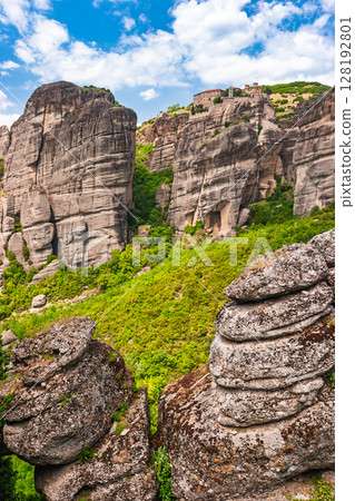Medieval monastery perched on massive rock formations above lush green valley in Meteora Greece Medieval monastery perched on massive rock formations above lush green valley in Meteora Greece 128192801