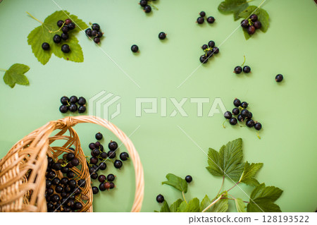 Ripe blackcurrants in a basket on a green background 128193522