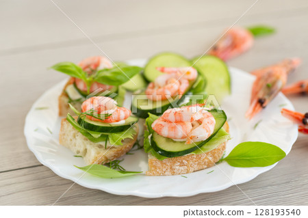 Delicious portioned appetizers with shrimps and greens on a wooden table Delicious portioned appetizers with shrimps and greens on a wooden table 128193540