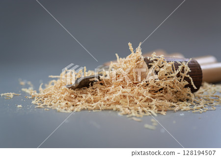 Hand tool and shavings after wood carving on gray background 128194507