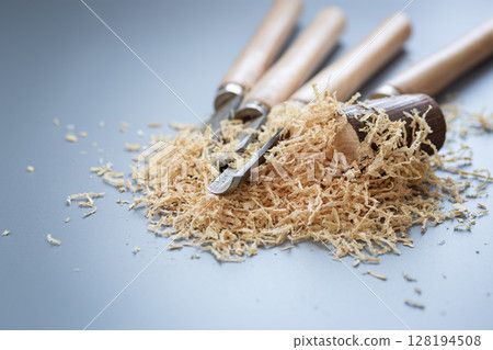 Chisels and wood shavings in craftsman's workshop on gray background 128194508
