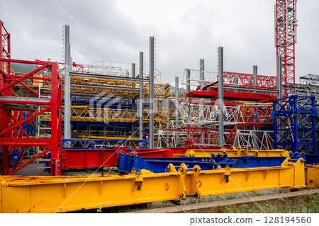 Colorful construction crane parts stored outdoors at industrial site 128194560
