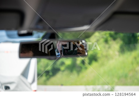 Photographer taking picture through rearview mirror inside car 128194564