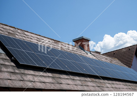 Solar panels installed on tiled roof of residential house in sunny weather 128194567