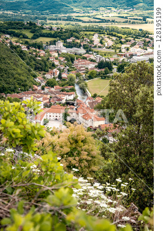 Picturesque View Of Vipava From Castle Ruins: Red-Tiled Rooftops And Church Tower Nestled In Green Valley With Blooming Flowers In Foreground And Rolling Fields In Background, Slovenia 128195199
