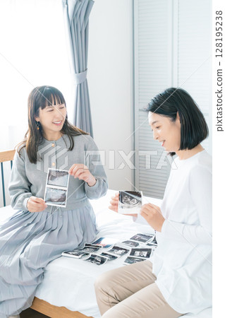 母親和女兒在臥室裡查看超音波影像，等待嬰兒出生 128195238