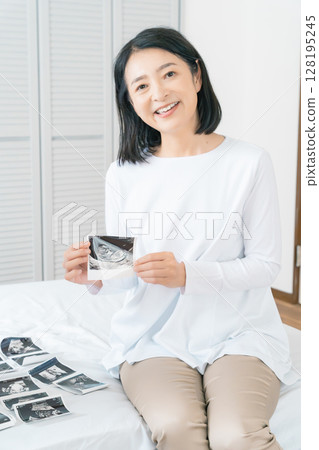 母親和女兒在臥室裡查看超音波影像,等待嬰兒出生 母親和女兒在臥室裡查看超音波影像,等待嬰兒出生 128195245