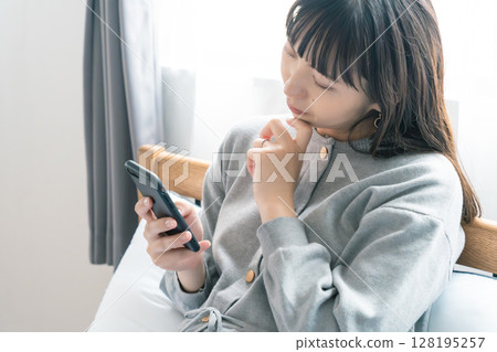 A pregnant woman checking a list for preparing for birth in her bedroom 128195257