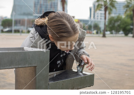 Kid drinking water from a fountain 128195701