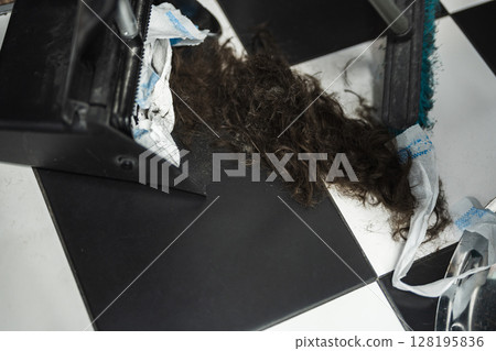 Hair clippings gathered at a barbershop during a busy salon day Hair clippings gathered at a barbershop during a busy salon day 128195836