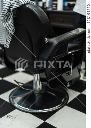 Classic black barber chair set against a checkered floor in a stylish barbershop Classic black barber chair set against a checkered floor in a stylish barbershop 128195850