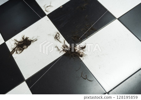 Clumps of hair scattered on a black and white tiled floor in a salon Clumps of hair scattered on a black and white tiled floor in a salon 128195859