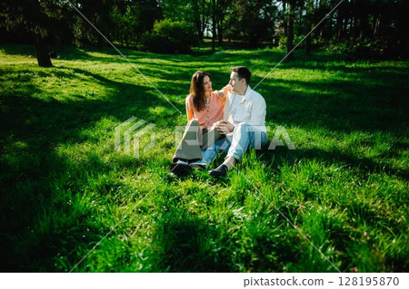 Couple enjoying a sunny moment in a serene green park setting 128195870