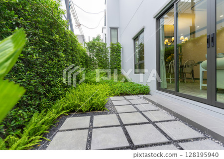 Modern design home garden landscaping. Flower garden and green plant with brick border and pedestrian pathway. Modern design home garden landscaping. Flower garden and green plant with brick border and pedestrian pathway. 128195940