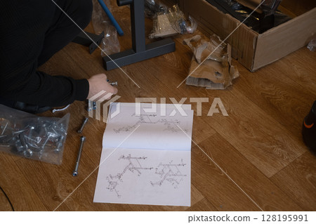 Man installs fitness equipment at home creating a comfortable space for workouts and exercise routines. Man installs fitness equipment at home creating a comfortable space for workouts and exercise routines. 128195991