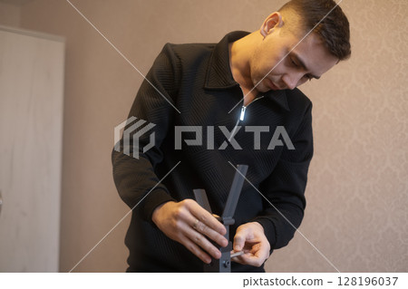 Experienced craftsman assembling furniture in a home setting offering professional furniture installation services. Experienced craftsman assembling furniture in a home setting offering professional furniture installation services. 128196037