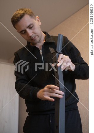 Furniture expert assembles furniture at home transforming empty space into a comfortable stylish living area. Furniture expert assembles furniture at home transforming empty space into a comfortable stylish living area. 128196039