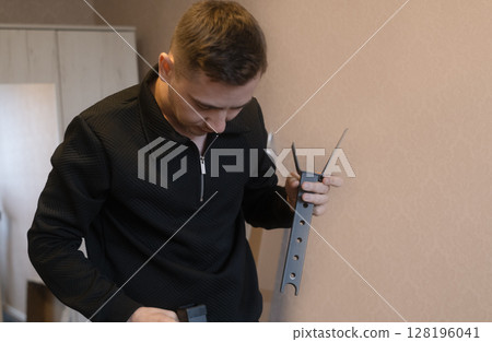 Man carefully assembling furniture parts creating a strong and reliable interior for a comfortable living space. 128196041