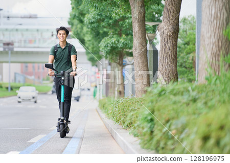 一名年輕男子在自行車道上騎電動滑板車 128196975