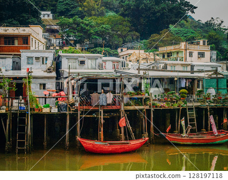 Traditional Stilt Houses In Hong Kong Village: Colorful Weathered Structures Built On Wooden Pilings Amid Urban Surroundings And Mountain Backdrop In Southeast Asia Traditional Stilt Houses In Hong Kong Village: Colorful Weathered Structures Built On Wooden Pilings Amid Urban Surroundings And Mountain Backdrop In Southeast Asia 128197118
