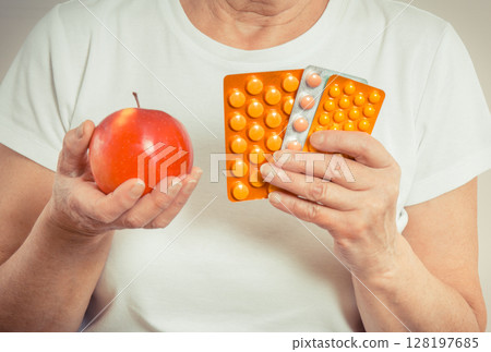 Senior woman with tablets or supplements and fresh apple 128197685