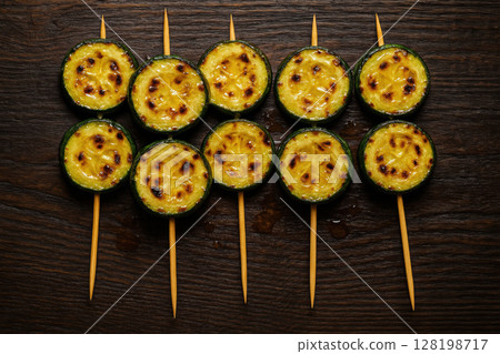 Grilled zucchini skewers arranged in a pattern on dark wooden surface, showcasing charred marks and vibrant colors, AI Generative Grilled zucchini skewers arranged in a pattern on dark wooden surface, showcasing charred marks and vibrant colors, AI Generative 128198717