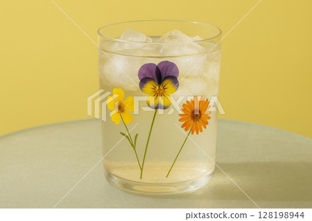 Refreshing ice cold beverage in a clear glass decorated with vibrant edible flowers on a minimalist pastel background, AI Generative 128198944