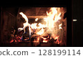 Burning fire logs inside stone fireplace. Close-up view. 128199114
