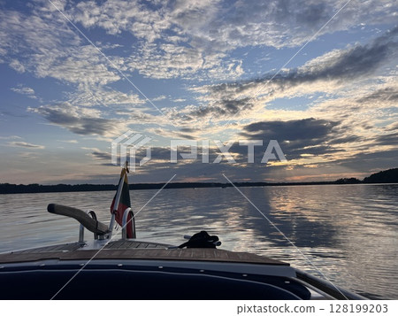 Sunset view of the back of a cruise ship with seating areas and the wake behind the ship Sunset view of the back of a cruise ship with seating areas and the wake behind the ship 128199203