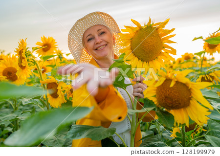 A Joyful Smiling Woman Standing Among Large Sunflower Field Wearing a Stylish Hat A Joyful Smiling Woman Standing Among Large Sunflower Field Wearing a Stylish Hat 128199979