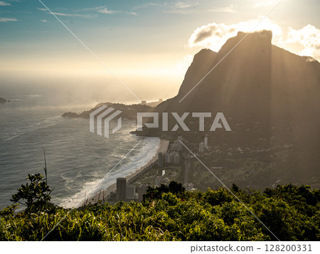 Golden Sunset Over Rio De Janeiro From Two Brothers Mountain: Dramatic Sunbeams Streaming Through Coastal Peaks Above The Atlantic Ocean And Leblon Beach 128200331