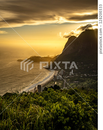 Golden Sunset Over Rio De Janeiro From Two Brothers Mountain: Dramatic Sunbeams Streaming Through Coastal Peaks Above The Atlantic Ocean And Leblon Beach Golden Sunset Over Rio De Janeiro From Two Brothers Mountain: Dramatic Sunbeams Streaming Through Coastal Peaks Above The Atlantic Ocean And Leblon Beach 128200333
