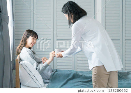 Mother giving drink to pregnant daughter 128200662