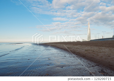 Beautiful sunrise on beach of park St. Petersburg is 300 years old on Gulf of Finland. Calm smooth water with cirrus clouds reflected, St. Petersburg, Russia 128200715