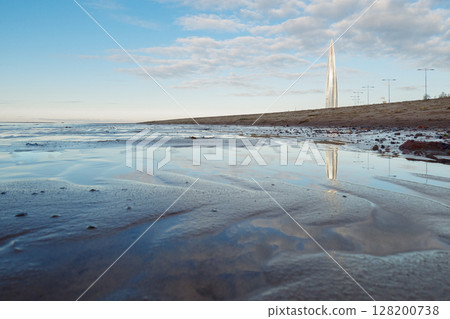Beautiful sunrise on beach of park St. Petersburg is 300 years old on Gulf of Finland. Calm smooth water with cirrus clouds reflected, St. Petersburg, Russia 128200738